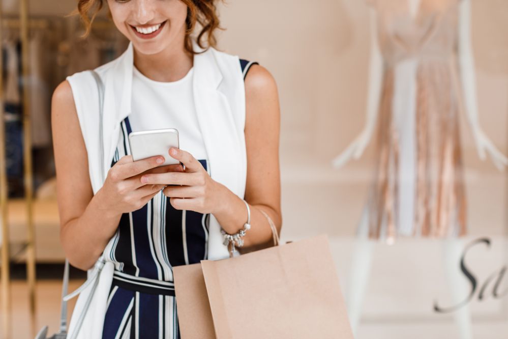 Cropped unrecognisable Caucasian woman standing outdoors and typing on her smartphone.
