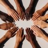 Grupo de mãos de pessoas com diferentes tons de pele formando um círculo, simbolizando diversidade, pertencimento e comunidade de marca no varejo.