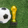 FIFA World Cup in retail concept featuring a soccer ball and championship trophy on a grass field, representing experiential marketing and consumer engagement opportunities.